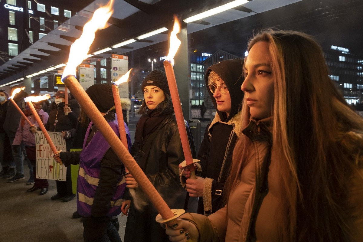 Une femme manifestent avec des torches lors d'un rassemblement suite a la 26eme victime de feminicide en Suisse et contre les violences faites aux femmes, ce mardi 21 decembre 2021 a Geneve. (KEY ...