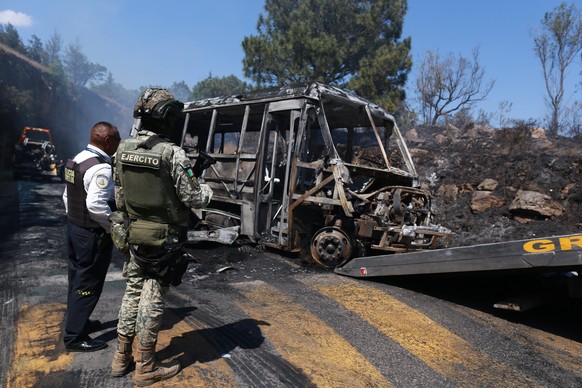 A soldier stands guard by a charred vehicle that was set on fire in Cointzio, Mexico, Sunday, Feb. 22, 2026, amid reports the Mexican Army killed Jalisco New Generation Cartel leader Nemesio Oseguera, ...