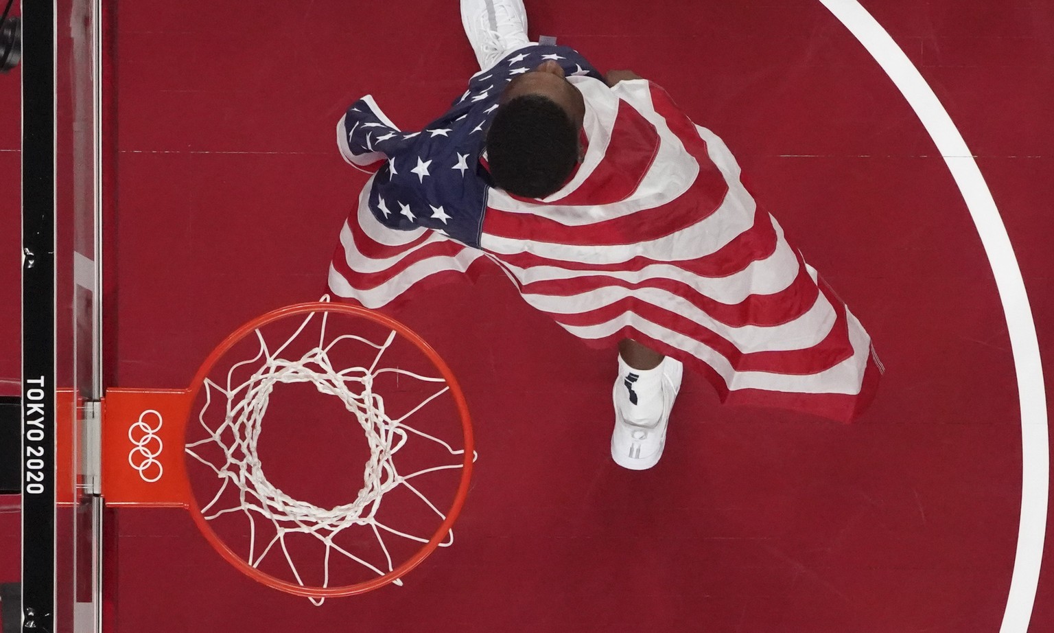United States&#039; Bam Adebayo (13) walks off the court with a flag draped over his shoulders after the team&#039;s win over France in a men&#039;s basketball gold medal game at the 2020 Summer Olymp ...