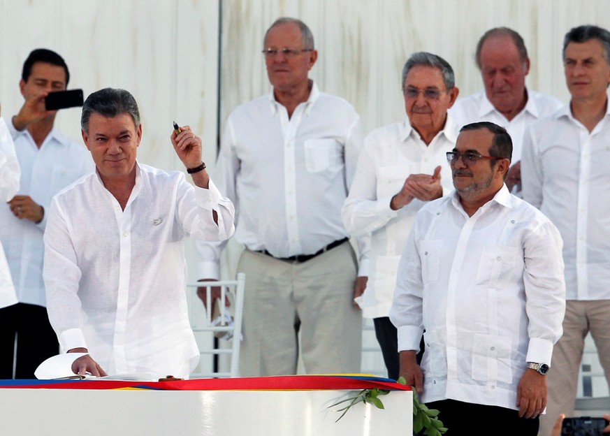 Colombian President Juan Manuel Santos (L) holds a pen made from a bullet before signing an accord ending a half-century war that killed a quarter of a million people, as Marxist rebel leader Rodrigo  ...