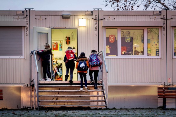 Pupils go to a school which is partially located in containers in Frankfurt, Germany, Monday, Dec. 14, 2020. Germany goes into a lockdown on Wednesday, Dec. 16, 2020. (AP Photo/Michael Probst)