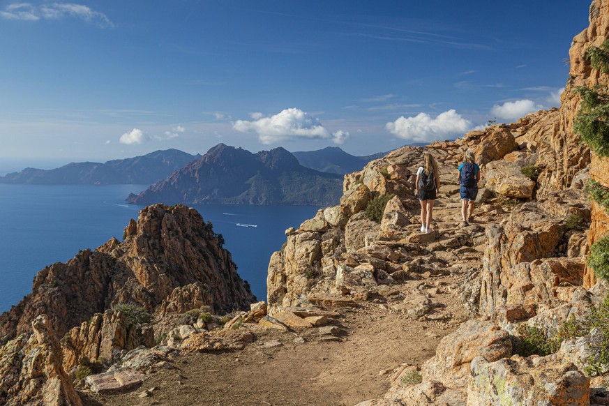 zwei Wanderer laufen in der Calanche einer bizarre Felsenlandschaft an der Suedkueste des Golfs von Porto im Regionalen Naturpark Korsika Frankreich Europa zwei Wanderer laufen in der Calanche einer b ...