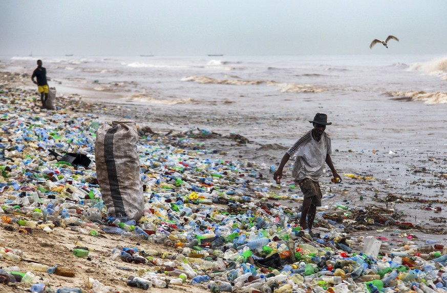 epa05361332 A photograph made availavble 13 June 2016 shows a Ghanaian collecting recyclable material at the polluted Korle Gono beach, that is covered in plastic bottles and other items washed ashore ...