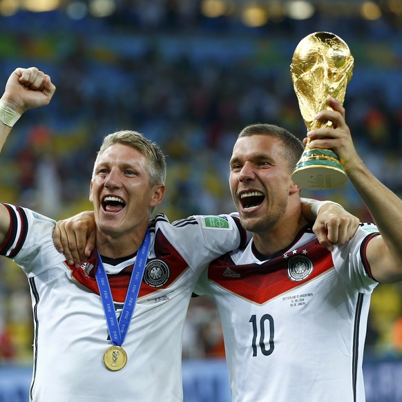 Schweini und Poldi grinsen mit dem WM-Pokal.