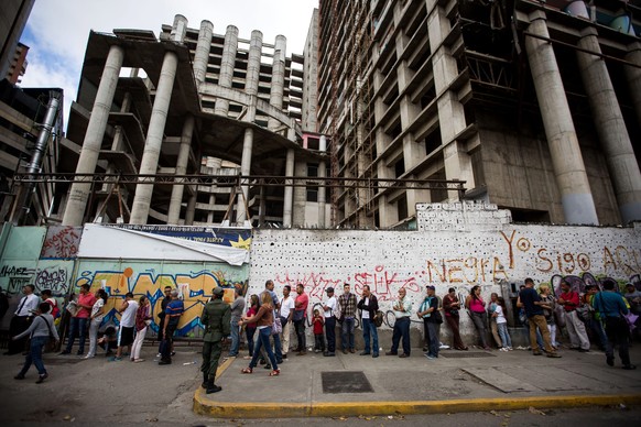 epa05674370 Venezuelans make a line outside a bank in Caracas, Venezuela, 13 December 2016. Thousands of Venezuelans head to the banks to get rid of their 100 Bolivares bills, the highest denomination ...