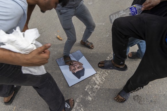 epa12364614 Protesters step on a picture of resigned Prime Minister K.P. Sharma Oli while storming the Singha Durbar palace, which houses government and parliament buildings, during violent demonstrat ...