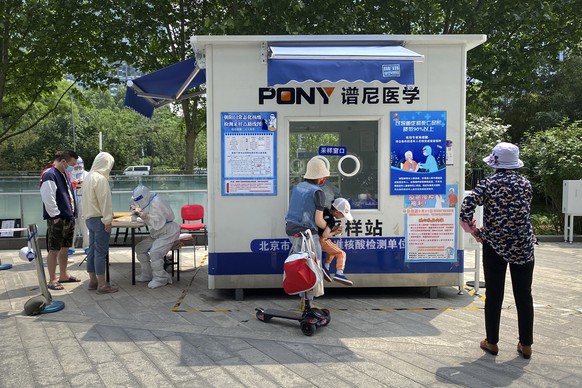 A worker wearing a protective suit registers people for COVID-19 tests at a coronavirus testing site in Beijing, Thursday, May 19, 2022. Parts of Beijing on Thursday halted daily mass testing that had ...