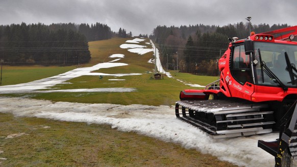 ARCHIV - 03.02.2020, Bayern, Thalkirchdorf: Eine Pistenraupe steht auf einer Skipiste, die bei Tauwetter noch teilweise mit Schneeresten bedeckt ist. (Zu dpa "Winter in Europa war der wärmste sei ...