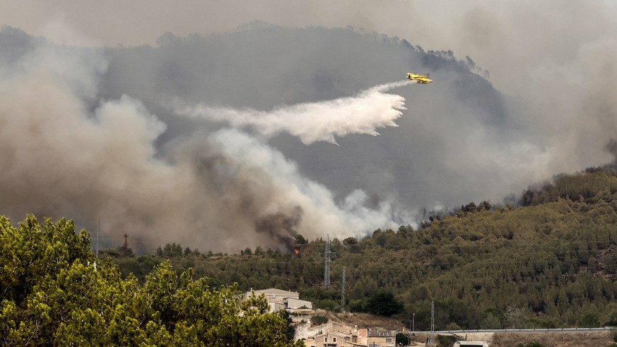 epa10076248 A firefighting aircraft drops water on a forest fire originated in Pont de Vilomara, Spain, 17 July 2022. The fire has burnt 440 hectares so far. EPA/TONI ALBIR