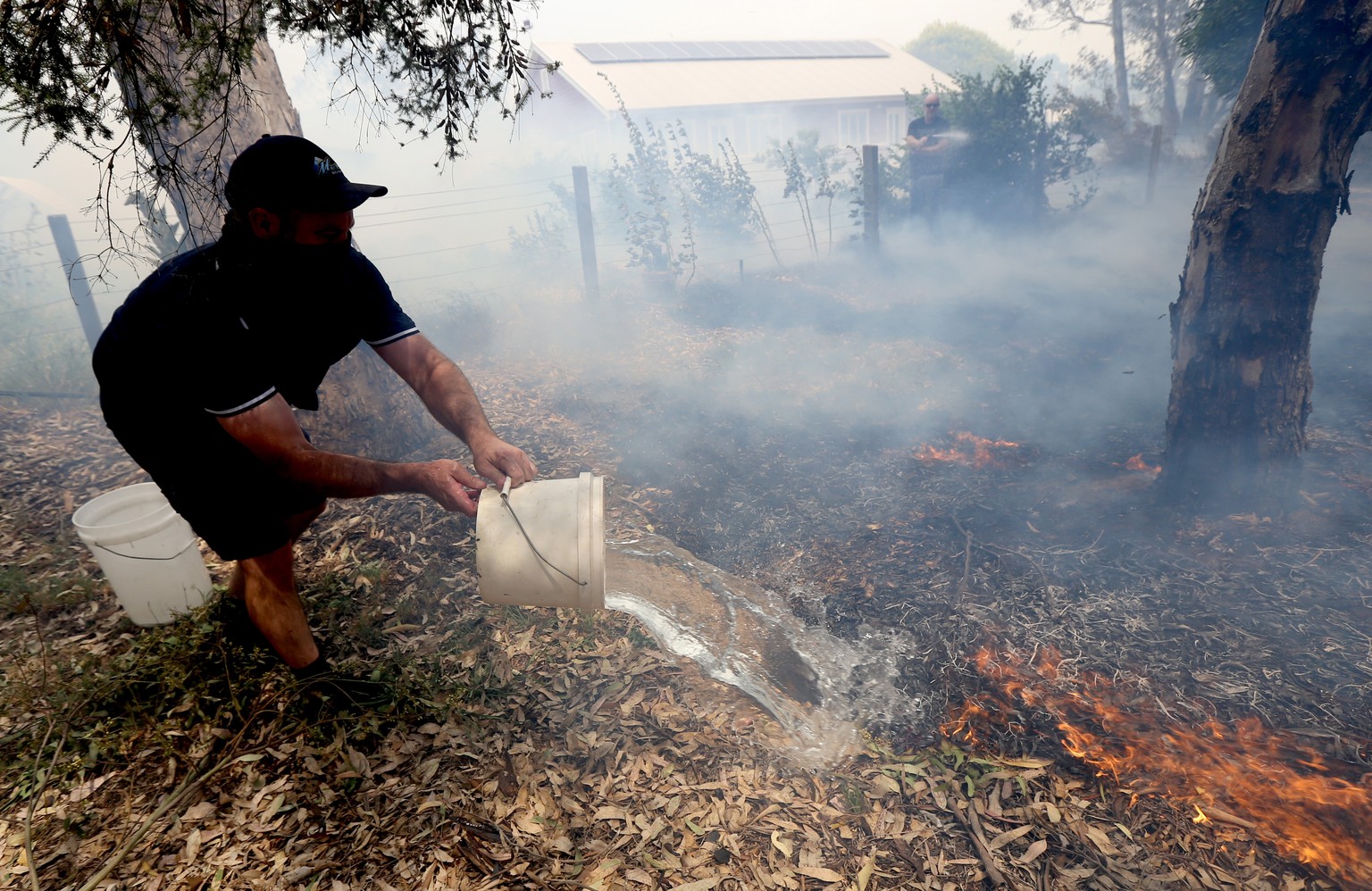 Vergeblicher Kampf gegen das Feuer: Ein Einwohner von Adelaide im Südwesten Australiens versucht die Flammen mit Wasserkübeln zu löschen.