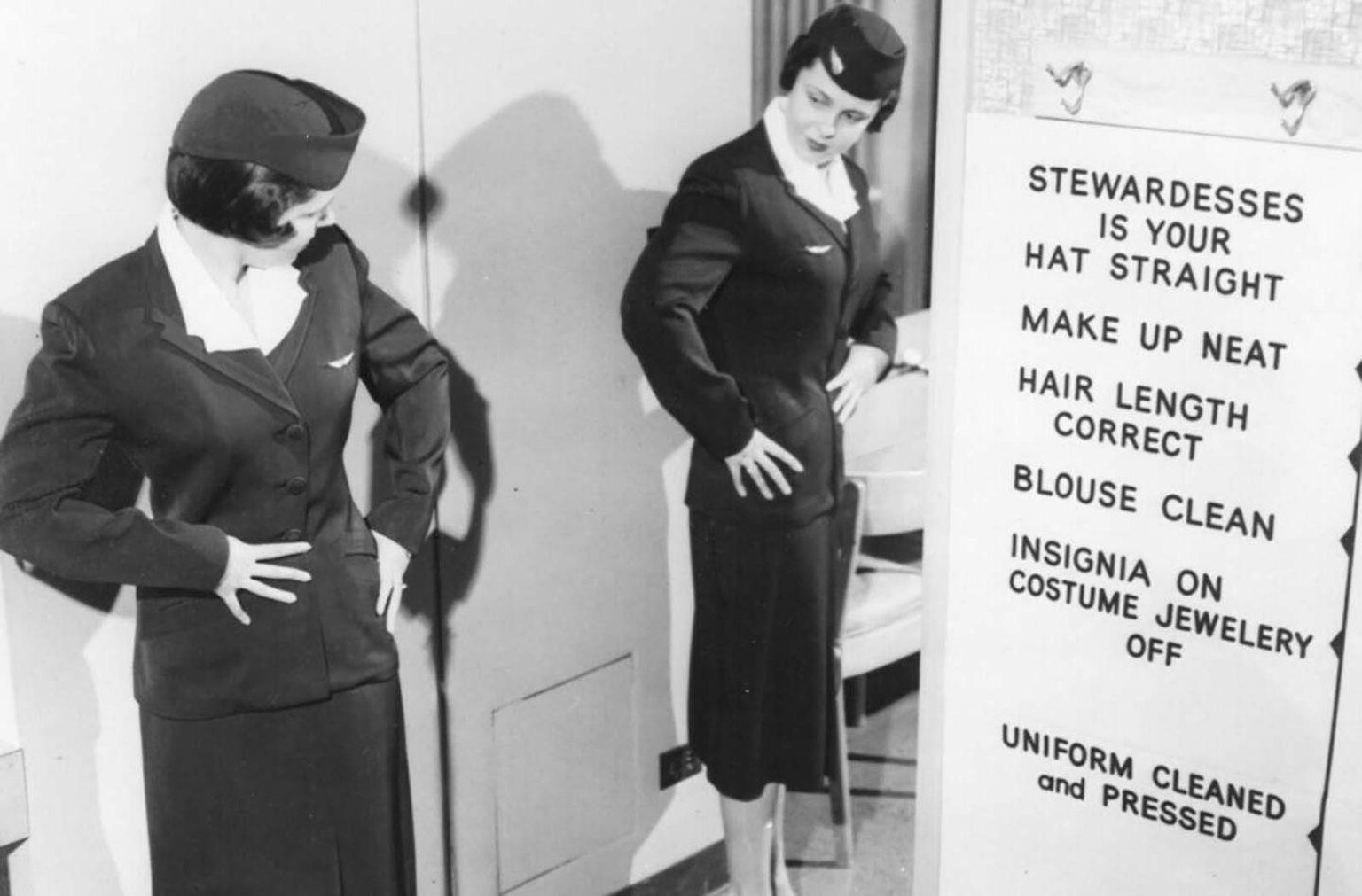A stewardess checks her reflection in a mirror against a grooming checklist covering hat, makeup, hair length, and blouse cleanliness, USA, 1950s
