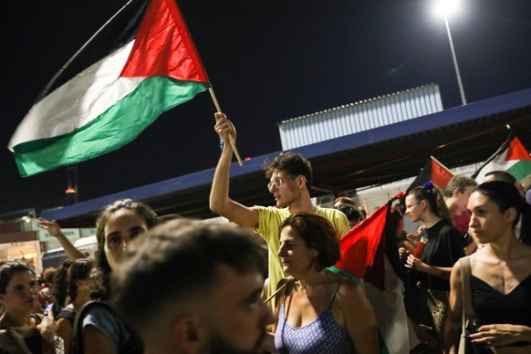 epa12242026 A demonstrator waves the Palestinian flag during a protest rally at a pier in Perama port, where the cargo ship Cosco Shipping Pisces is expected to dock, in Piraeus, Greece, 16 July 2025. ...