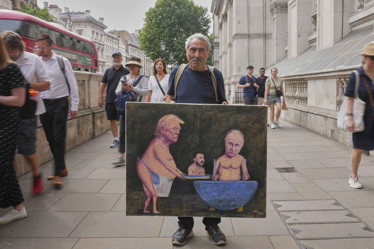 Satirical artist Kaya Mar, displays his latest painting depicting President Trump, Russian President Putin and Ukraine's President Zelenskyy, outside Downing Street, in London, Wednesday, Aug. 13 ...