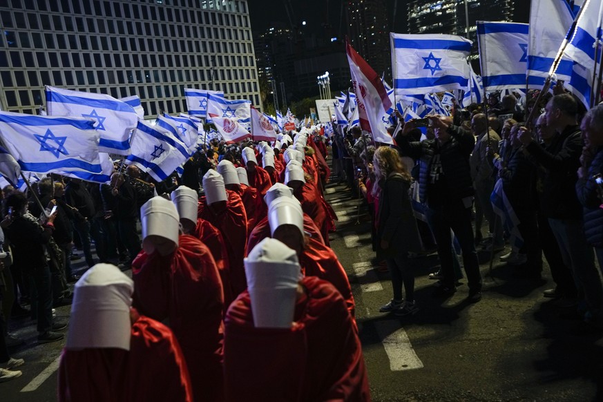 A line of protesters supporting women&#039;s rights dressed as characters from The Handmaid&#039;s Tale television series and other Israelis protest against plans by Prime Minister Benjamin Netanyahu& ...