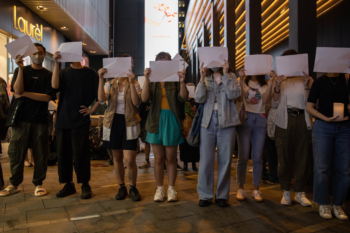 epa10334255 Mourners hold blank sheets of paper during a vigil for the victims of China