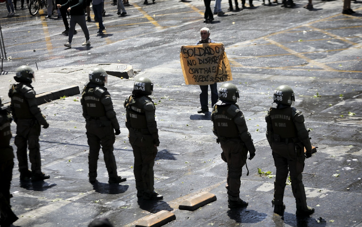 A protester holds a banner that reads in Spanish &quot;Soldier don&#039;t fire against the people&quot; in front of riot police during in Santiago, Chile, Wednesday, Oct. 23, 2019. Rioting, arson atta ...