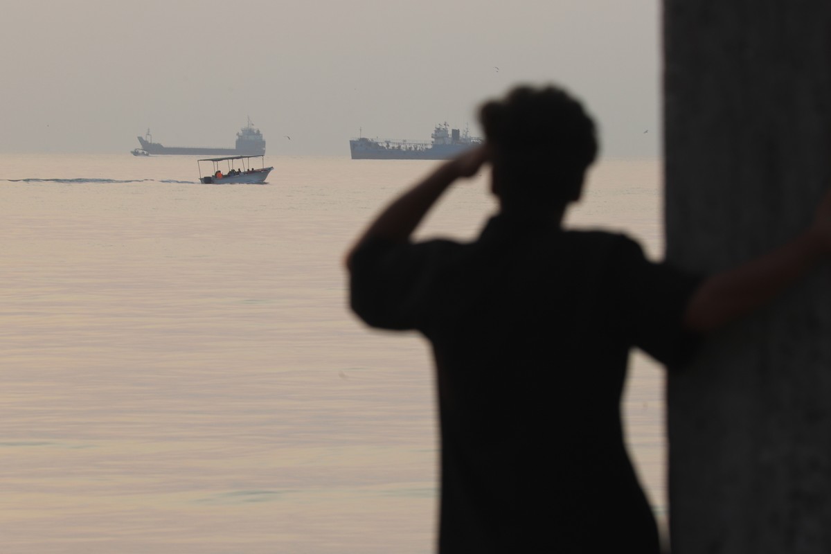 A man looks out over the water as a small boat passes cargo ships anchored in the Strait of Hormuz off Bandar Abbas, Iran, early Saturday, Oct. 24, 2026. (Amirhosein Khorgooi/ISNA via AP)
Iran Strait  ...