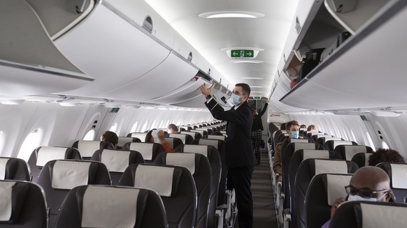 epa08486912 A cabin crew member of Swiss International Air Lines, wearing a face mask, prepares the aircraft prior to departure to London at the Geneva Airport, in Geneva, Switzerland, 15 June 2020. F ...