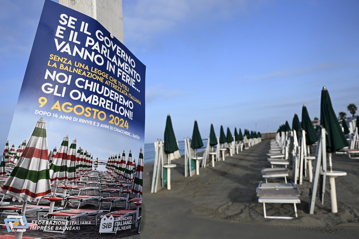 epa11538866 A poster calling for a strike is seen beside deck chairs and umbrellas closed during a two-hour strike by beach operators at the Belsito beach in the seaside resort of Ostia, outside Rome, ...