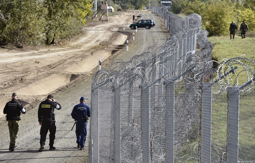 epa05583622 A police officer (C) and border guard (L) from Poland patrol with a Hungarian policeman (R) along the temporary border fence on the Hungarian-Serbian border near Roszke, 180 kms southeast  ...