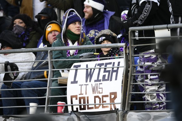 A fan holds a sign in freezing temperatures during the second half of an NFL football game between the Baltimore Ravens and the Atlanta Falcons, Saturday, Dec. 24, 2022, in Baltimore. (AP Photo/Nick W ...
