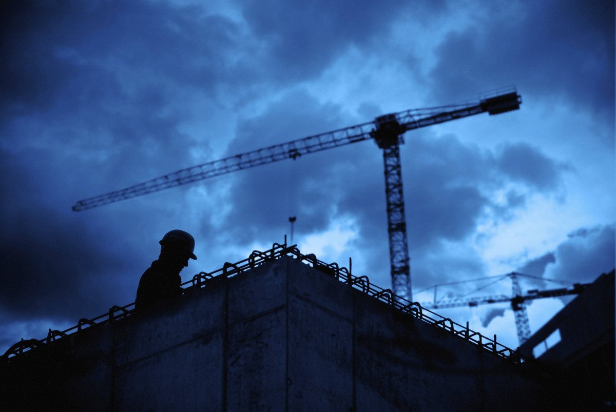 Silhouette eines Bauarbeiters auf einer Baustelle vor stürmischem Himmel, Prag, Tschechische Republik Silhouette of a construction worker on a site against a stormy sky, Prague, Czech Republic Copyrig ...