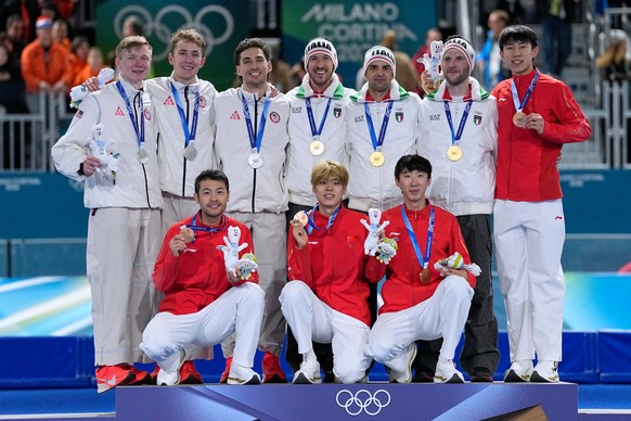 Team Italy, center and gold medal, team USA, left and silver medal, and team China, right and bronze medal, celebrate on the podium of the men's team pursuit speedskating race at the 2026 Winter  ...