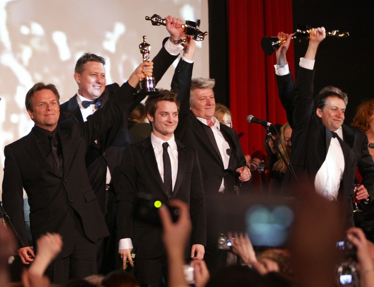 Members of the cast and production crew of "The Lord of the Rings: The Return of the King" hold up their Oscar awards as fans cheer at the American Legion Hall in the Hollywood section of Lo ...