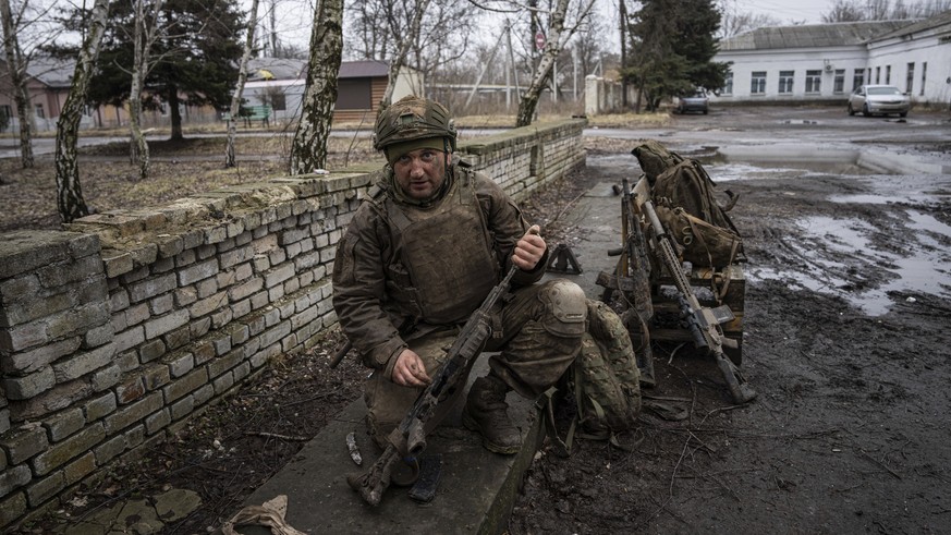 A Ukrainian serviceman who recently returned from the trenches of Bakhmut cleans his gun in Chasiv Yar, Ukraine, Wednesday, March 8, 2023. (AP Photo/Evgeniy Maloletka)