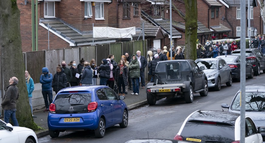 Members of the public queue outside a vaccination centre in Manchester as the UK aims to increase booster jab rollout to 1m a day to battle an Omicron &#039;tidal wave&#039; Manchester, England, Monda ...