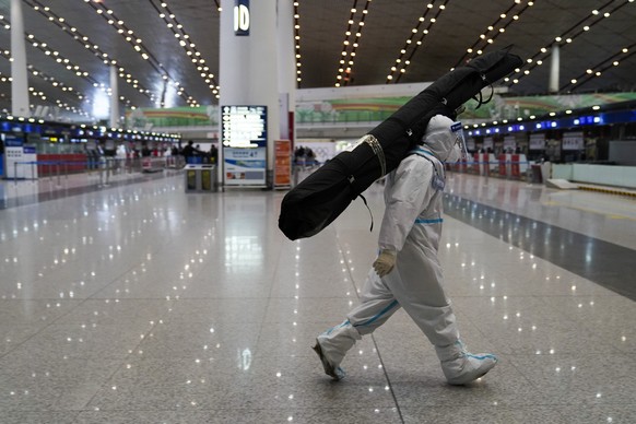 A volunteer carries a passenger&#039;s luggage at Beijing-Capital International Airport after the conclusion of the 2022 Winter Olympics, Sunday, Feb. 20, 2022, in Beijing. (AP Photo/Ashley Landis)