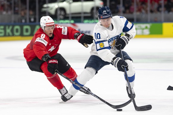 epa12995900 Switzerland's Simon Knak, left, fights for the puck against Finland's Henri Jokiharju, right, during the 2026 IIHF Men's Ice Hockey World Championship preliminary round grou ...