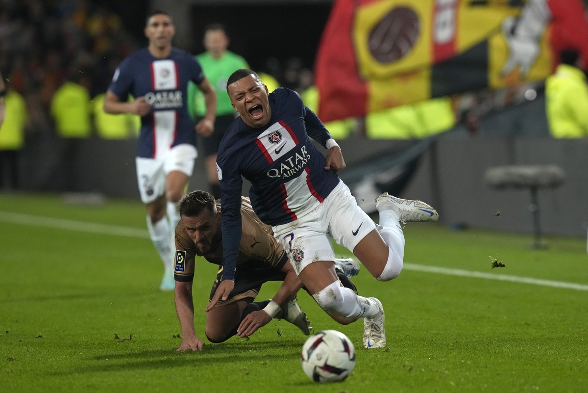 PSG's Kylian Mbappe is sent flying by a challenge from Lens' Jonathan Gradit during the French League One soccer match between Lens and Paris Saint-Germain at the Bollaert stadium in Lens, F ...