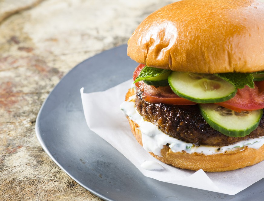 This image released by Milk Street shows a recipe for Indian-spiced pork burgers. The garam masala, cayenne and cumin first are mixed into a paste made from tangy yogurt, egg yolk and breadcrumbs, whi ...