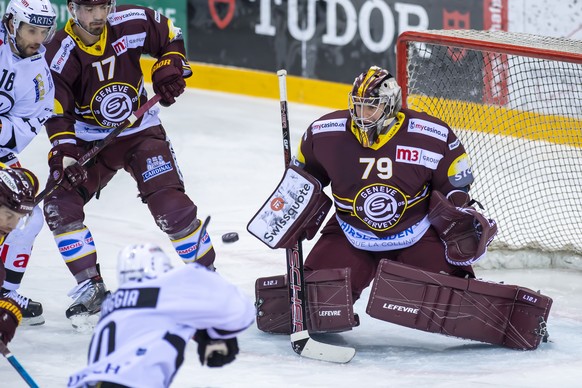 L&#039;attaquant luganais Alessio Bertaggia, gauche, a la lutte pour le puck avec le gardien genevois Daniel Manzato, droite, lors du match du championnat suisse de hockey sur glace de National League ...