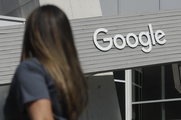 FILE - In this Sept. 24, 2019, file photo a woman walks below a Google sign on the campus in Mountain View, Calif. Alphabet will report earnings after markets close, Tuesday, Oct. 26, 2021. (AP Photo/ ...