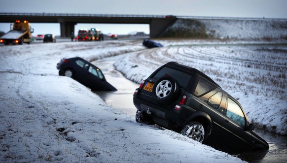epa03498310 Cars lie in a dyke on the side of the road after skidding off due to ice and snow on the roads near Zurich, in the direction of Bolsward, the Netherlands, 06 December 2012. EPA/CATRINUS VA ...