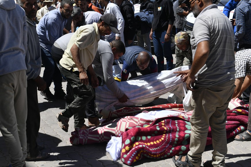epa10850722 A group of men lines up the bodies of people killed in an earthquake in Marrakesh, Morocco, 09 September 2023. A powerful earthquake that hit central Morocco late 08 September, killed 1,03 ...
