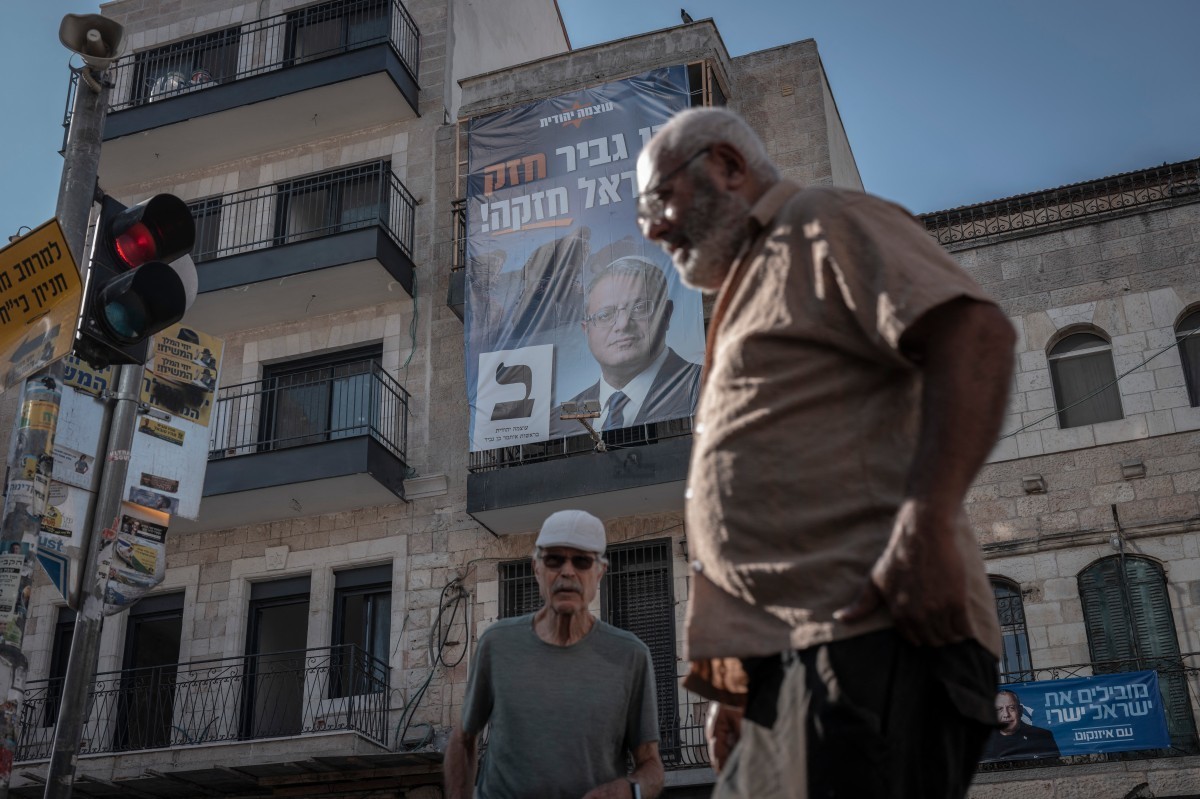 Isarelis walk past a campaign banner of National Security Minister Itamar Ben Gvir's far-right Otzma Yehudit party in Jerusalem on October 18, 2026. Israel heads to the polls on October 27 in its ...