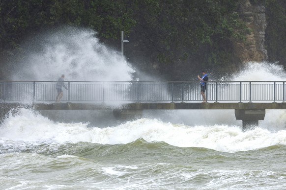 People watch as waves crash against the cliffs at an Auckland beach as a cyclone hits the upper parts of New Zealand, Sunday, Feb. 12, 2023. New Zealand&#039;s national carrier has canceled dozens of  ...