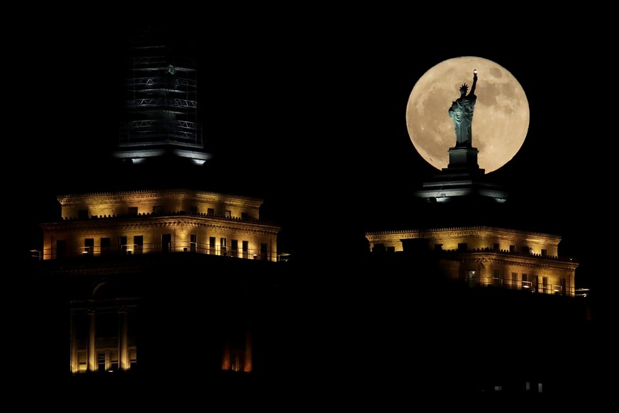 A supermoon rises in front of a replica of the Statue of Liberty sitting atop the Liberty Building in downtown Buffalo, N.Y., Sunday, Dec. 3, 2017. December&#039;s full moon appears bigger and brighte ...