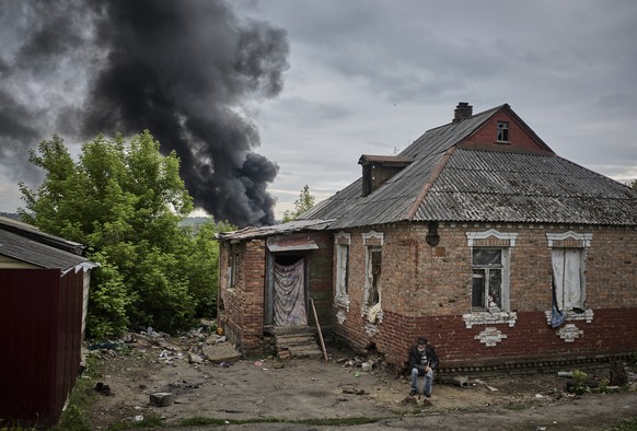 epaselect epa11348680 A local man sits near his damaged home as smoke rises after shelling, on the outskirts of Kharkiv, Ukraine, 17 May 2024, amid the Russian invasion. More than 9,000 residents from ...