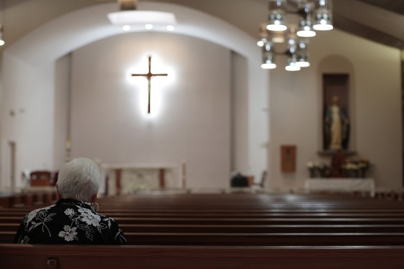 epa09975435 A woman prays inside Sacred Heart Catholic Church as police and investigators continue to work at the scene of a mass shooting at the Robb Elementary School which killed 19 children and tw ...