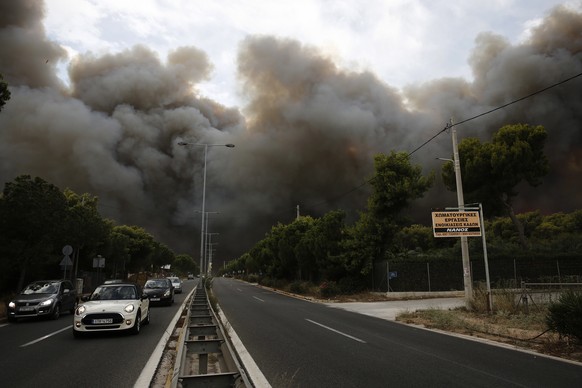 epa06906630 Smoke rise over an avenue during a forest fire in Neo Voutsa, a northeast suburb of Athens, Greece, 23 July 2018. After the wildfire in Kineta a second wildfire broke out in the Penteli Mo ...