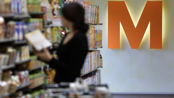 Eine Frau begutachtet am 9. Maerz 2005 in der Migros-Filiale in Embrach ein Produkt. Das orange M prangt auf der Wand hinter ihr. (KEYSTONE/Gaetan Bally)