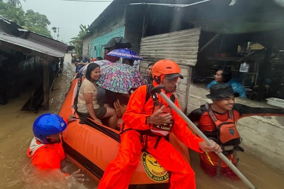 In this photo released by the Indonesian National Search and Rescue Agency (BASARNAS), rescuers on a rubber boat evacuate residents from their flooded home in North Sumatra province, Indonesia Tuesday ...