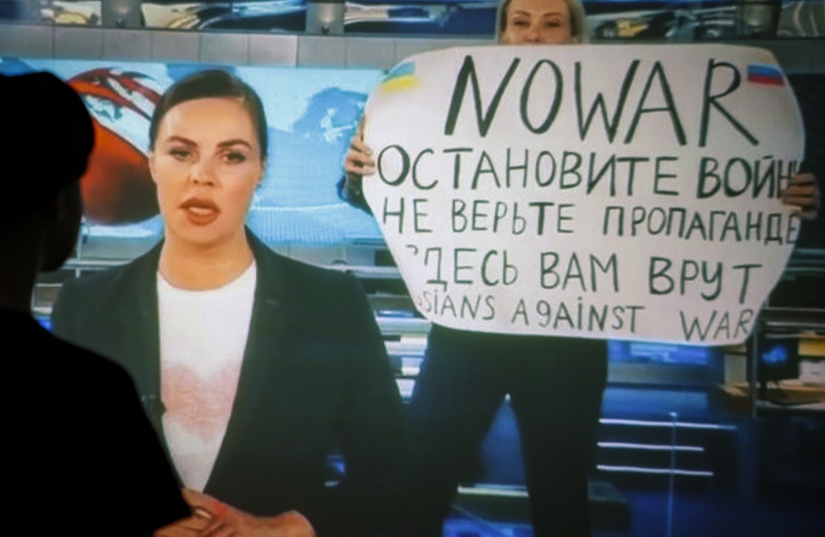 epaselect epa09826233 A woman watches a recorded feed of the Russian Channel One's evening news broadcast TV show in which an employee enters Ostankino on-air TV studio with a poster reading  ...