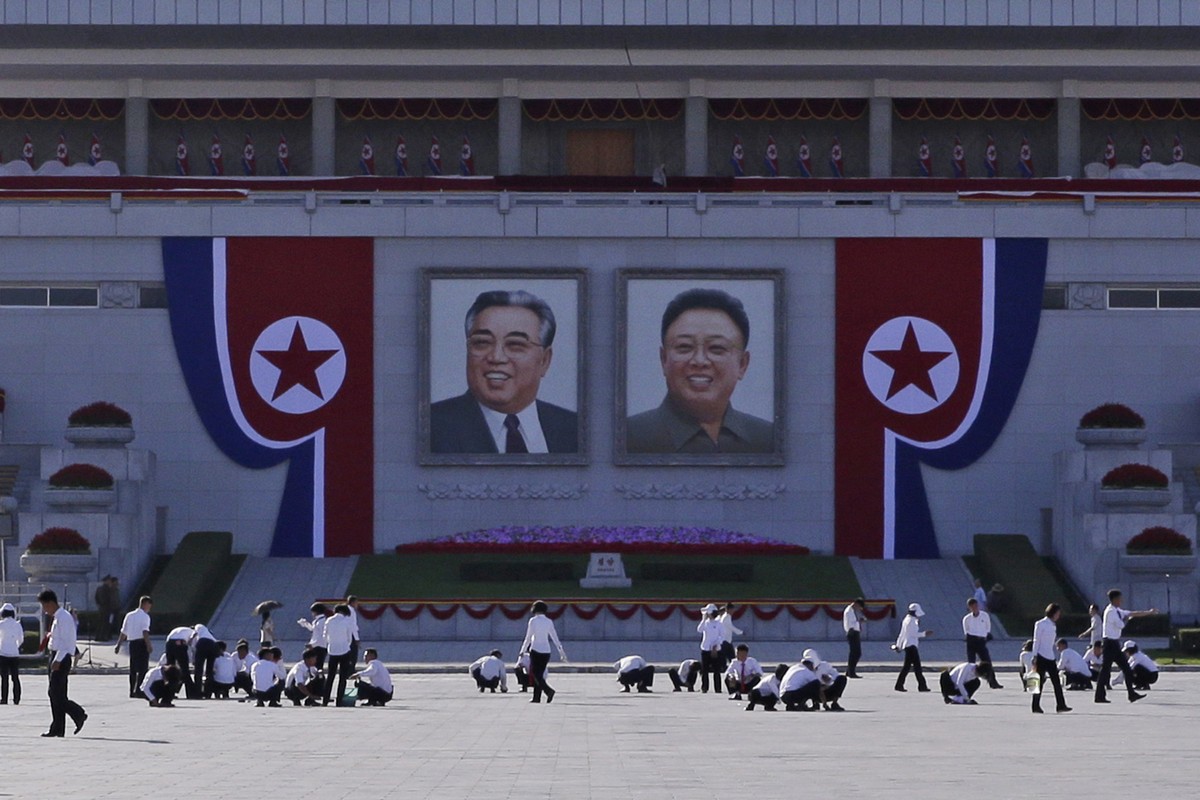North Koreans prepare under portraits of the country's late leaders, Kim Il Sung, left, and Kim Jong Il, right, on Kim Il Sung Square, ahead of the 70th anniversary of North Korea's founding ...
