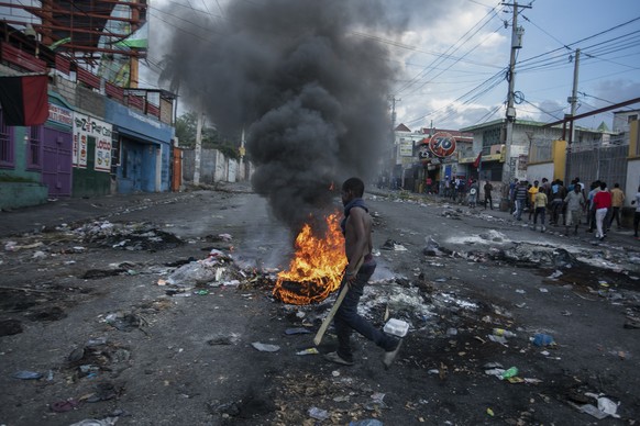 A man walks past burning tires set up by protesters during a protest demanding the resignation of Prime Minister Ariel Henry in the Delmas area of Port-au-Prince, Haiti, Monday, Oct. 10, 2022. (AP Pho ...