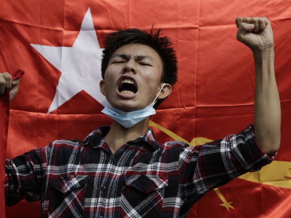 epa09711507 (31/31) (FILE) - A protester shouts slogans in front of a National League for Democracy (NLD) flag during a protest against the military, in Yangon, Myanmar, 06 February 2021 (reissued 27  ...